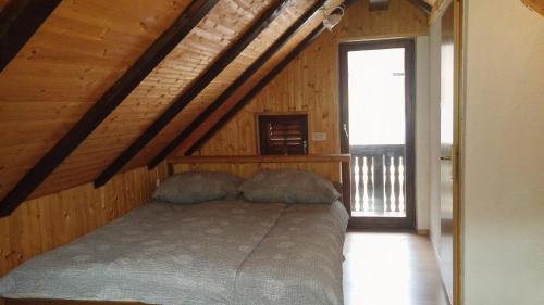 a bedroom with a bed in a wooden attic at Hisa V Sadovnjaku in Logje
