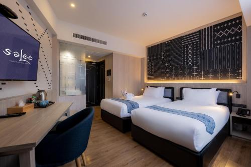 a hotel room with two beds and a desk at Salee Boutique Hotel in Chiang Mai
