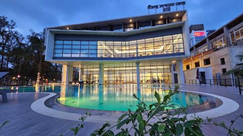 a large building with a swimming pool in front of it at SSK Urmee in Cox's Bazar