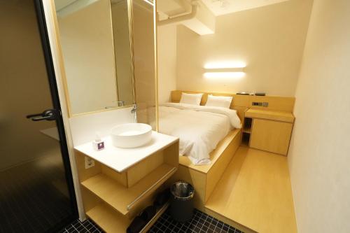 a bathroom with a bed and a sink and a mirror at Connected Hotel Nonhyeon in Seoul