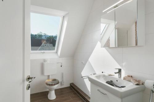 a white bathroom with a sink and a toilet at Fewo Tief Blick in Dornum