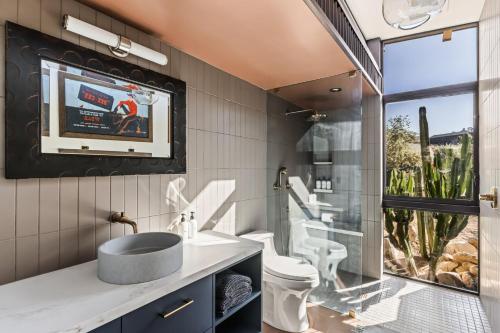 a bathroom with a sink and a tv on the wall at Mod West Ranch: 5-acre Boulder Playground in Pioneertown