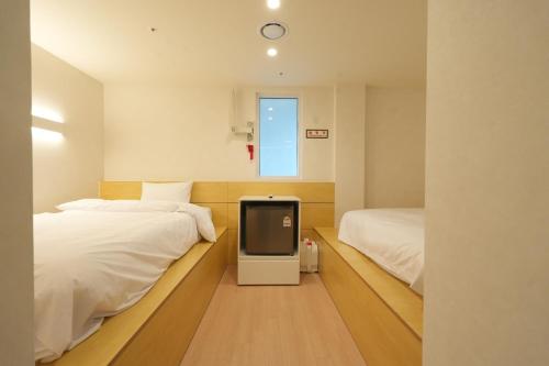 a bedroom with two beds and a tv in it at Connected Hotel Nonhyeon in Seoul