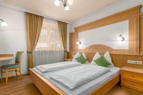a bedroom with a large bed and a chair at Residence Diana Apartment 103 in Terento