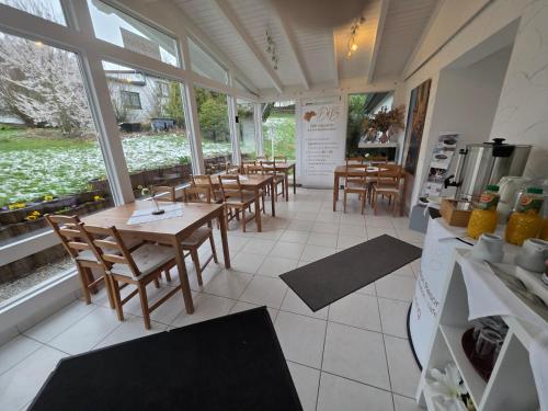 a restaurant with wooden tables and chairs and windows at Ferienwohnung Büffel in Niedenstein
