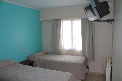 a room with two beds and a window with a tv at Cabo Vírgenes in Río Gallegos