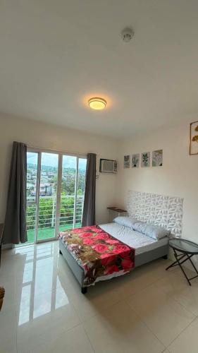 a bedroom with a bed and a large window at Modena Town Square Minglanilla in Minglanilla