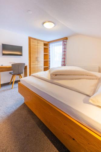 a bedroom with a large bed and a desk at Haus Hubertus in Galtür
