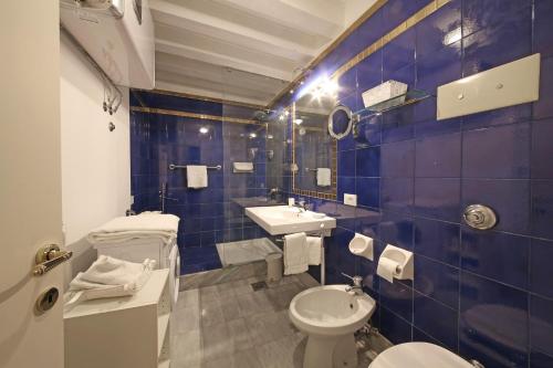 a blue tiled bathroom with a toilet and a sink at Appartamenti inside Palazzo Foscarini in Venice