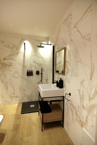 a bathroom with a white sink and a marble wall at Residenza Basiglio in Ceva