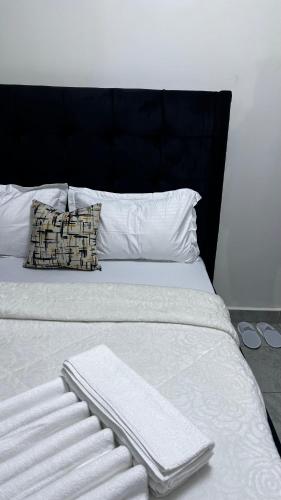 a white bed with a black headboard and white pillows at Authentic Galore in Ongata Rongai 