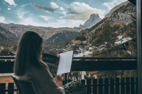 a woman reading a book on a balcony with mountains at central sky-penthouse with iconic matterhorn view in Zermatt