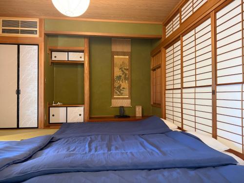 a bedroom with a blue bed in a room with windows at 伊勢神楽別邸 in Ise