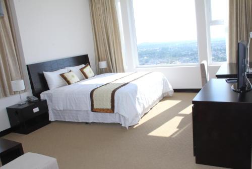 a hotel room with a bed and a large window at Sai Gon Ban Me Hotel in Buon Ma Thuot