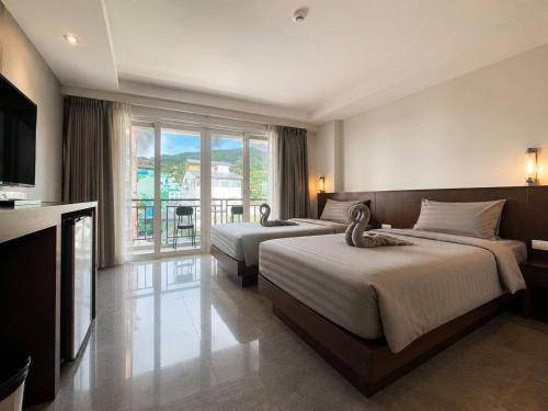 a hotel room with two beds and a television at Doze Bangla in Patong Beach