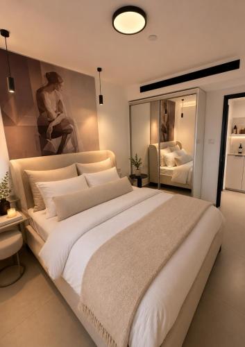 a bedroom with a large white bed with a painting on the wall at נווה ים סוף - מתחם דירות נופש פרימיום באילת in Eilat