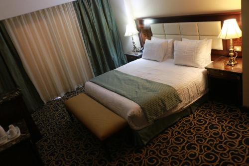 a hotel room with a bed and a table and lamps at The Guard Hotel in Cairo