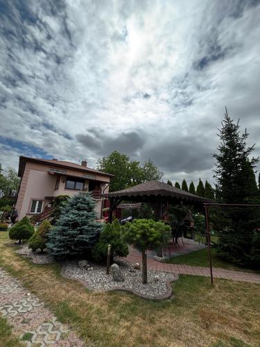 a house with a table and an umbrella in a yard at Wypoczynek pod leszczynami in Sitno
