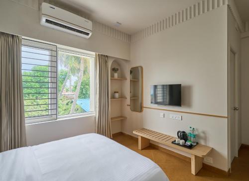 a bedroom with a bed and a tv and a window at Parthas Suites in Tiruchirappalli