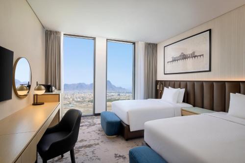 a hotel room with two beds and a desk at DoubleTree by Hilton Madinah Gate in Medina