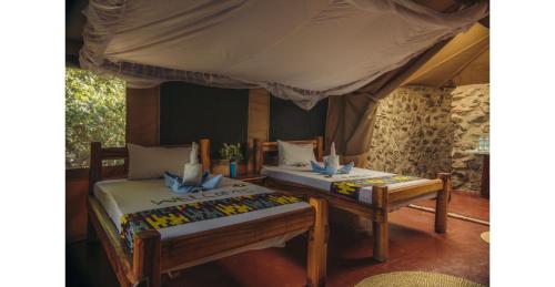 a bedroom with two beds and a canopy at Lake Natron Tented Camp in Mtowabaga