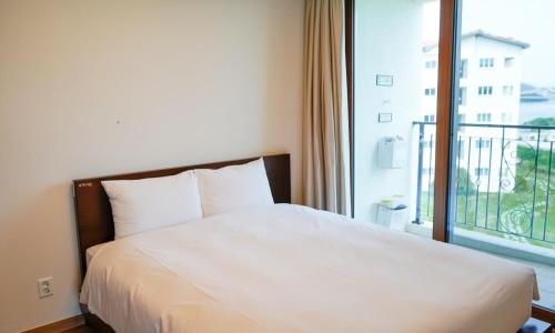a bed in a hotel room with a large window at Sagewood Yeosu Gyeongdo Resort in Kyŏngho-dong