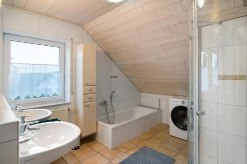 a bathroom with a tub and a sink and a washing machine at Ferienwohnung "Am Hennenberg" in Erlenmoos