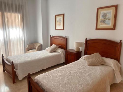 a bedroom with two beds and a chair and a window at Aurora in Teruel