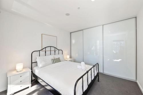 a white bedroom with a bed and glass walls at 1BR-1BR-1Car-Sleeps 4-Pool-CBD in Canberra
