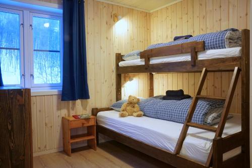 a teddy bear sitting on a bed in a bedroom at Cabin Huskyfarm Innset in Innset