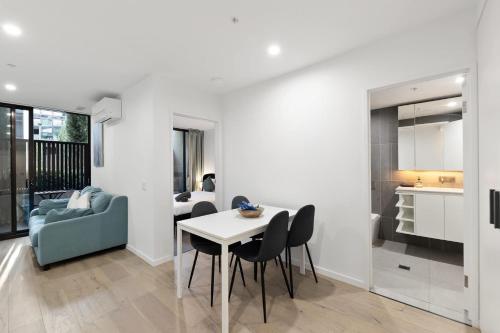 a kitchen and a living room with a table and chairs at 2B-1BR-1Car-Courtyard-CBD-Shops in Canberra