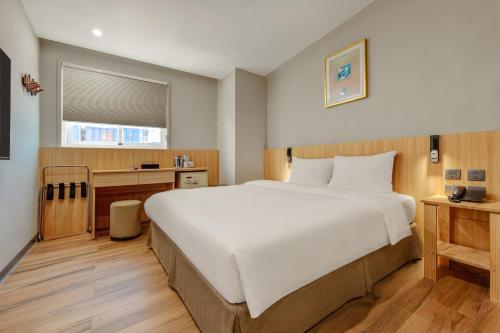 a bedroom with a large white bed and a desk at Whiyori Inn in Kaohsiung