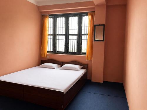 a small bedroom with a bed and a window at Hilltop Horizon Hotel in Bandipur