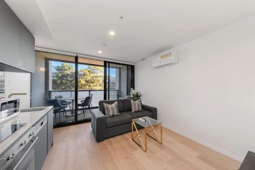 a kitchen and living room with a couch and a table at Central CBD - parking - sleeps 4 in Canberra
