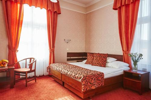 a bedroom with a bed and a chair and a window at Hotel Astoria in Balatonfüred