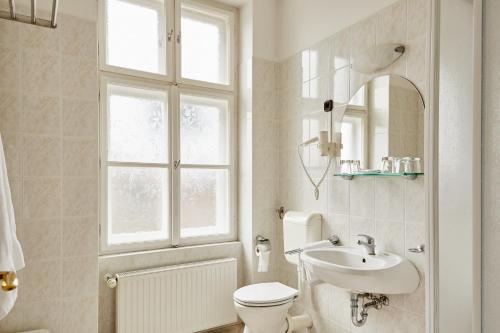 a bathroom with a toilet and a sink and a window at Hotel Astoria in Balatonfüred