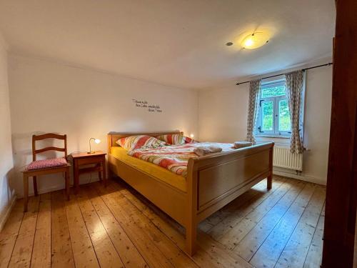 a bedroom with a bed and a chair and a window at Weiherhof in Ehrenberg