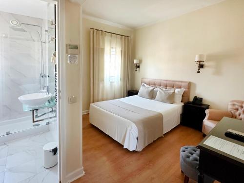 a hotel room with a bed and a bathroom at Hotel Joao Padeiro in Aveiro