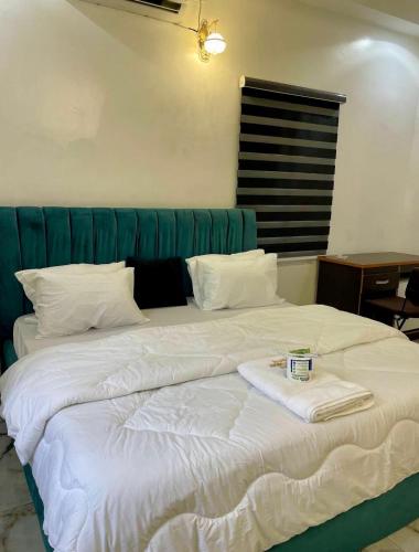 a large white bed in a bedroom with a green headboard at St Kora Apartment and Shortlets in Asaba