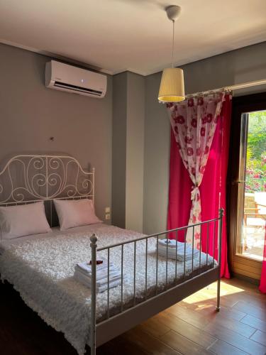 a bedroom with a bed with pink curtains and a window at Villa iliotropio in Lefokastro