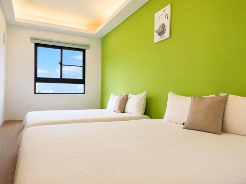 two beds in a room with a green wall at 若家民宿 台東縣民宿1275號 in Guanshan