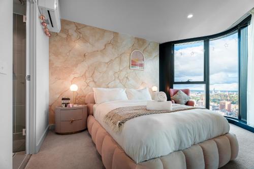 a bedroom with a large bed with a stone wall at Zen Sky Home - Super Centre with Free Car park & Pool in Melbourne