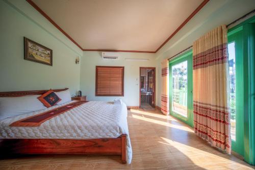 a bedroom with a bed and a large window at Tam Coc Cosiana Hotel in Ninh Binh