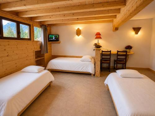 a bedroom with two beds and a table with a chair at Hotel la Fontaine du Mont Blanc in Les Houches