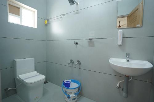 a white bathroom with a toilet and a sink at Misty Suite Infopark in Cochin