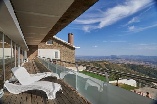 a balcony with two white chairs and a view at Alfândega da Fé Hotel & SPA in Sambade