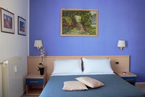 een blauwe slaapkamer met een bed met 2 kussens bij Città Eterna Guest House in Rome