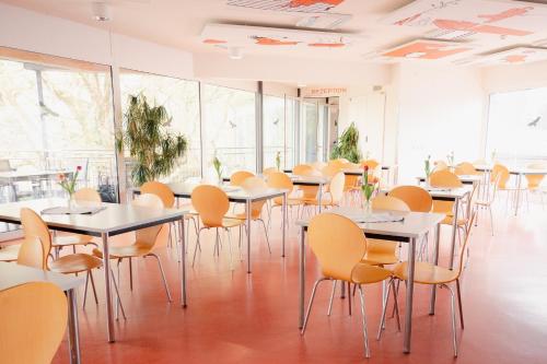 a row of tables and chairs in a room with windows at Junges Hotel Hard am Bodensee in Hard