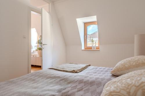 a white bedroom with a bed and a window at Hakuna Rooftop Penthouse Wachau in Spitz