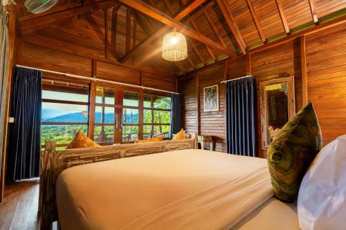 a bedroom with a large bed in a room with wooden walls at Pondok Nyoman Bedugul by AGATA in Bedugul